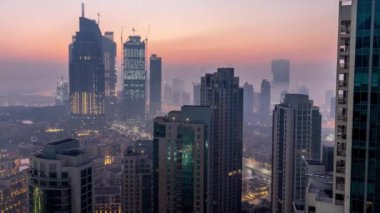 Sisli sabah gün geçiş timelapse gecesine Dubai şehir merkezinde. Şehir gökdelenler fütüristik görünümünü sis kaplı. Çatı güneş doğmadan önce havadan görünümden. Dubai, Birleşik Arap Emirlikleri