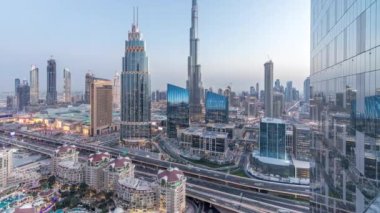 Dubai şehir merkezi, UAE 'deki en yüksek bina ve karayolu trafiğiyle gece gündüz geçiş zamanı. Günbatımından sonra modern kulelerle gökdelenin çatısından gökyüzü manzarası