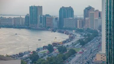 Dubai creek peyzaj gün gece geçiş timelapse tekneler ve yatlar ile ve trafik yol ve otopark ile modern binalar. Yukarıdan hava üstten görünüm