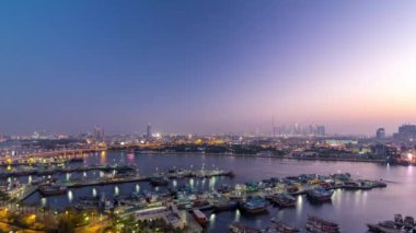 Dubai Deresi manzara panoraması günden geceye geçiş zamanı tekneler, yatlar ve yollarda trafiği olan modern binalar. Yukarıdan hava üstü görünümü