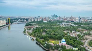 Nehir, köprü, park ve merkez iş bölgesiyle şehir merkezi üzerindeki hava manzarası günden geceye geçiş zamanı çatısı, Orta Asya, Nur-Sultan şehri, Kazakistan