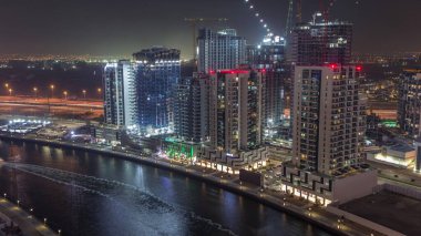 Dubai, Birleşik Arap Emirlikleri 'ndeki Business Bay hava sahasındaki gece kuleleri. Kanalla yukarıdan inşaat alanı görünümü