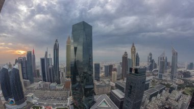 Sheikh Zayed karayolu zaman çizelgesinde Dubai 'deki finans merkezinde gün batımına sahip gelecekçi gökdelenlerin manzarası. Yukarıdan gökyüzü turuncu bulutlu