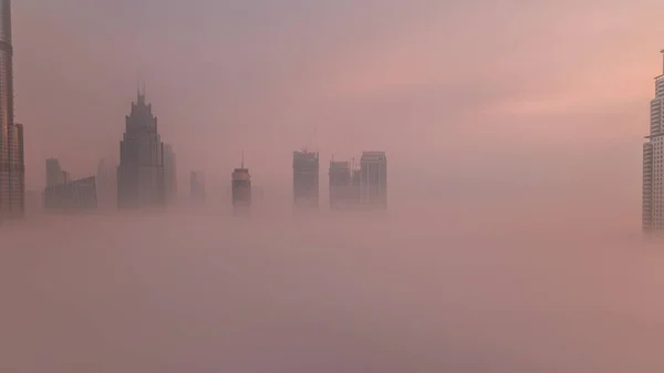 空中からの眺め朝の霧がドバイ国際金融センター地区のタイムラプスを覆いました 日の出の間に近代的な高層ビルやモールがあるオフィスタワーとホテル — ストック写真