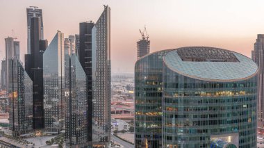 Dubai Uluslararası Finans Merkezi gökdelenleri hava gününden geceye geçiş zamanı. Yukarıdan parlayan pencere görünümlü aydınlık kuleler