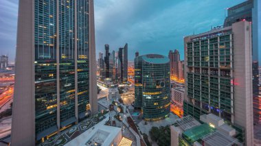 Dubai Uluslararası Finans Merkezi gökdelenleri panorama havacılık gece gündüz geçiş zamanı. Aydınlatılmış kuleler, bulutlu renkli gökyüzü ile güneş doğmadan önce yukarıdan görünürler