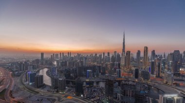 Dubai iş sahası ve şehir merkezindeki kulelerin modern mimarisi ile panoramik ufuk çizgisi günden geceye geçiş zamanı. Gün batımından sonra kanal ve şantiyeli hava manzarası