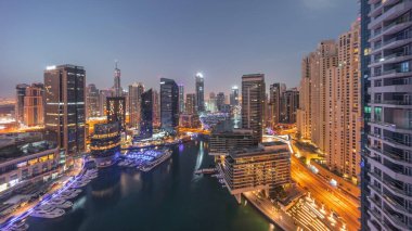 Dubai marinasının hava panoramik görüntüsü kanalın etrafındaki gökdelenleri gece gündüz yüzen yatlarla aydınlattı. Güneş doğmadan önce beyaz tekneler yat kulübüne park edilir.