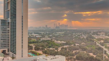 Zabeel bölgesinin bahçesinde gün doğumu, arka planda gökdelenler, Dubai, BAE 'de hava zaman aralığı. Gökyüzünde turuncu bulutlar ve güneş ışığı