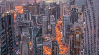 Dubai Marina 'nın gökdelenlerle çevrili Skyline manzarası kıyı şeridi boyunca gece gündüz geçiş zamanlarını gösteriyor. Gündoğumundan önce yüzen yatlar ve yol trafiği. Dubai, BAE