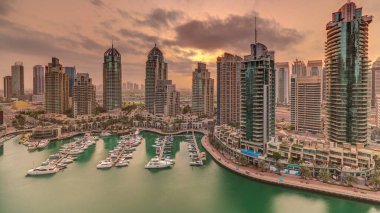 Dubai Marina turizm bölgesi üzerinde gündoğumu. Gökdelenler ve kanalın çevresindeki panoramik zaman çizelgeleri. Residential binalar ve caddelerdeki trafik