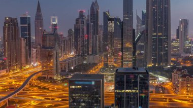 Dubai Finansal Merkezi 'nin panoraması. Gece gündüz aydınlatma saatleri olan yüksek gökdelenleri var. Gün doğmadan önce yoğun karayolu boyunca kulelerin hava görüntüsü