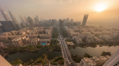 Barsha Heights bölgesindeki gökdelenler üzerinde gün doğumu ve Yeşiller bölgesindeki alçak katlı binalar tüm gün boyunca aşağı bakıyor. Dubai silueti sisli hava ve gölgelerle hızla ilerliyor