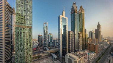 Dubai Uluslararası Finans Bölgesi 'nin hava panoramik görüntüsü. Gün boyunca birçok gökdelen zaman dilimi var. Çok katlı otoparkın yakınındaki yolda trafik vardı. Gölgeler hızla ilerliyordu. Dubai, BAE.