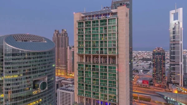 ドバイ国際金融センターの高層ビルは 夜間から昼間への移行時間が経過します 道路上の交通で日の出前からライトアップされた塔の景色 — ストック写真