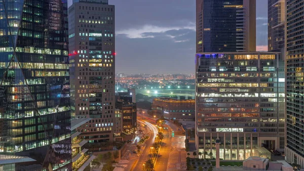 迪拜国际金融区夜以继日的过渡时间过去了 日出前商务大楼的空中景观 具有公路交通和Deira区背景的明亮摩天大楼 — 图库照片