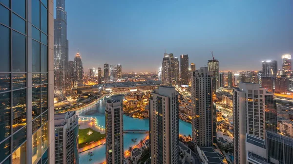 Dubai downtown with fountains and modern futuristic architecture aerial night to day transition timelapse before sunrise. Panoramic view to skyscrapers with old town and shopping mall