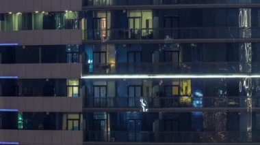 Modern ofisteki büyük parlayan pencereler ve konut binaları geceleri zaman ayarlı, sıralı pencereler ışık saçıyor.