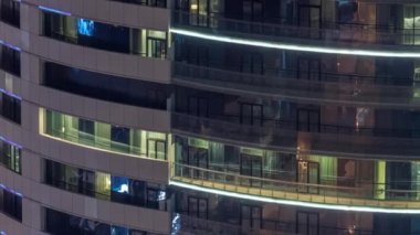 Modern konut binalarındaki büyük parlayan pencereler geceleri zaman ayarlı, sıra sıra parlıyor. Görüntüyü kapat