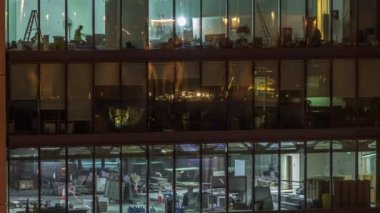 Modern ofis binalarındaki büyük parlayan pencereler geceleri zaman ayarlı, sıra sıra parlıyor. İşçiler içeride tadilat yapıyor.