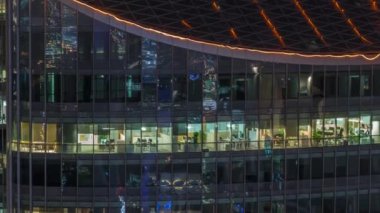Modern ofisteki büyük parlayan pencereler ve konut binaları gece saatlerine göre ayarlanıyor, pencereler ışık saçıyor. Finans bölgesinde gökdelenler