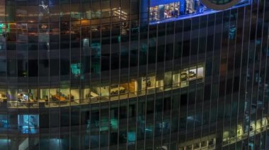 Modern ofisteki büyük parlayan pencereler ve konut binaları gece saatlerine göre ayarlanıyor, pencereler ışık saçıyor. Finans bölgesinde gökdelenler