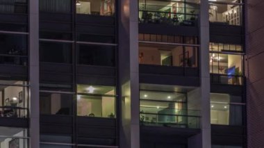 Modern ofisteki büyük parlayan pencereler ve konut binaları gece saatlerine göre ayarlanıyor, pencereler ışık saçıyor. Evde çalışma yeri
