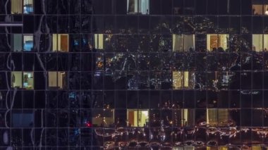 Modern ofisteki büyük parlayan pencereler ve konut binaları geceleri zaman ayarlı, sıralı pencereler ışık saçıyor.