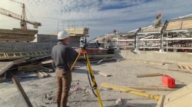 Construction worker using theodolite surveying optical instrument timelapse. Builders and carpenters in uniform working on the roof. Measuring angles in horizontal and vertical planes on construction