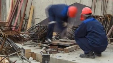 Yarı otomatik kaynak makinesinde çalışan kaynakçılar inşaat alanındaki bir zaman diliminde metal takviyesi yapıyorlar. Üniformalı ve mısırlı işçiler