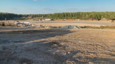 Panoramik peyzaj, mekanik zaman ayarlı kentsel alana dönüşür. Büyük bir tarlada ahşap evleri olan yeni kır köyü için şantiye manzarası. Mavi gökyüzünde güzel bulutlar