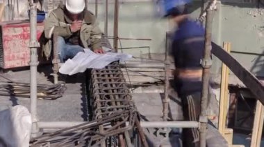 İnşaat alanında beton takviyesi için çelik çubuk inşaat iskeleti takviyesi. Ustabaşı inşaat planına bakıyor. Metal yeni bir binanın çatısında çalışıyor.
