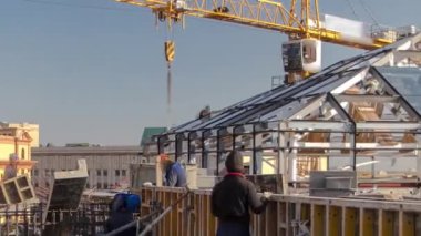 Sarı kule vinci. İnşaat alanında beton takviyesi için çelik çubuk inşaat iskeleti takviyesi. Üniformalı birçok işçiyle birlikte yeni bir binanın çatısında metal çalışıyor.