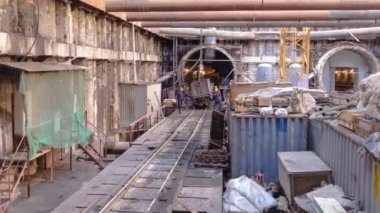 Cargo train in large huge ditch pit tunnel timelapse. Reinforcing structures from thick iron pipes of beams and structures at the construction site of the underground metro station line.