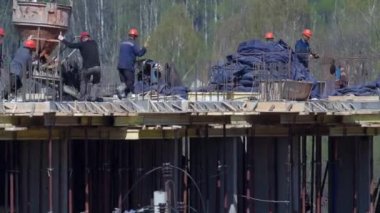 İnşaat halindeki binaları ve çok katlı evleri olan büyük bir inşaat alanı. Mavi gökyüzü arka planında faaliyet gösteren işçiler. Konut yenileme kavramı.