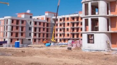 İnşaat halindeki binaları ve çok katlı evleri olan büyük bir inşaat alanı. Mavi gökyüzü arka planında kule vinçleri devrede. İşlem sırasında turna