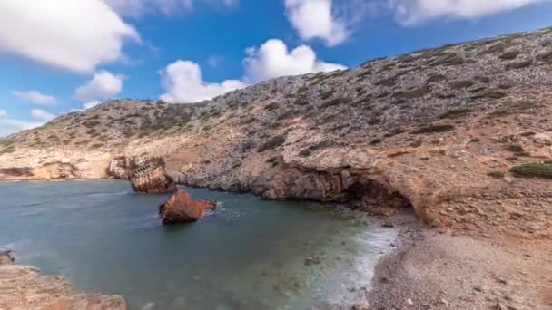 パノラマは ギリシャのアモーゴス島ナバジオビーチの澄んだ青い空の下で巨大な岩の形成の近くの海のタイムラプスで放棄された錆びた船を示しています — ストック動画