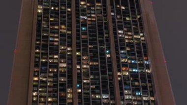 Modern ofis ve konut binalarındaki büyük parlayan pencereler gece görüş zamanlamasına bakar, pencereler ışık saçar.