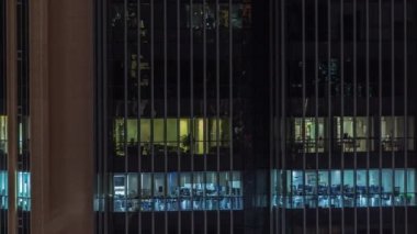 Modern ofis binalarındaki pencere ışıkları geceleri zaman ayarlı. Çok katlı gökdelenlerin içinde açık uzay odaları var. Masalarda çalışan insanlar