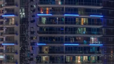 Gece vakitlerinde apartmanların pencereleri, evlerin pencerelerinden gelen ışık. Parlak kuleleri olan şehrin akşam manzarası