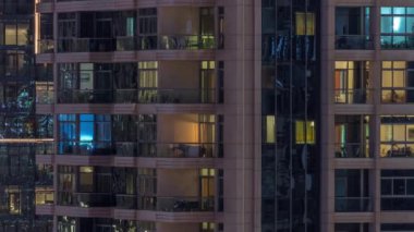 Gece vakitlerinde apartmanların pencereleri, evlerin pencerelerinden gelen ışık. Parlak odalı şehrin akşam manzarası