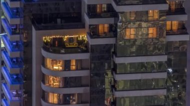 Modern kulelerin pencerelerinde ışık var. Geceleri parlayan pencereleri ve balkonları olan bir apartmanın dışında. Gökdelenin yukarıdan aydınlatmalı havadan görünüşü