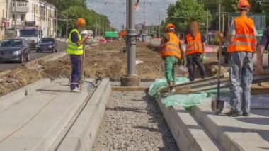 Yol onarımı için plakaların arasına beton dökülüyor. Bir sürü işçi ve mikser makinası var. Tramvay raylarının yeniden inşası
