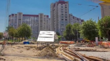 Sarı inşaat teleskopik vinç hareket halindeki tramvay rayları zaman ayarlı. Şapkalı ve üniformalı endüstriyel işçiler. Şehir caddesindeki tramvay raylarının yeniden inşası. Arka plandaki evler