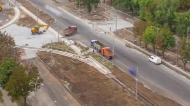 Büyük inşaat alanının panoramik hava görüntüsü. Buldozer, endüstriyel kamyon kazıcısı toprağı hareket ettiriyor ve bir çöp kamyonuna yüklüyor. Tramvay raylarının yeniden inşası