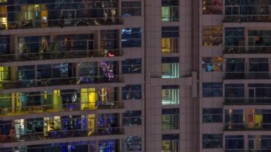 Dışarıdaki apartmanın gece manzarası renkli zaman çizelgesi. Pencere ve balkonlarında parlayan ışıklar olan yüksek gökdelen