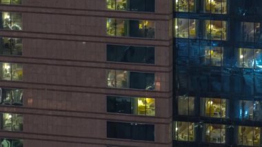 Panoramik pencerelerin dışında gece vakti üst sınıf bir binanın apartmanında. Gökdelende parlayan ışıklar