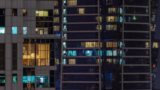 都市の光が空中のタイムラプスを反射して夜に輝くガラス張りの超高層ビルのアパートのパノラマ窓 ライトアップされた塔 — ストック動画