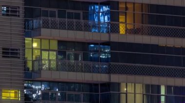 Pencereler gece aydınlatmalı modern cam bina zaman ayarlı. Parlayan ışıkları olan çok katlı gökdelenler..