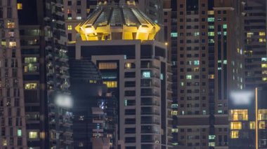 Parlak pencereli, dış apartman manzaralı bir zaman çizelgesi. Dubai marinasında ışıkları olan gökdelenler.